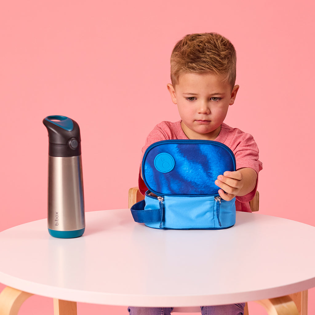 child opening b.box insulated snack bag in deep blue with sturdy carry handle