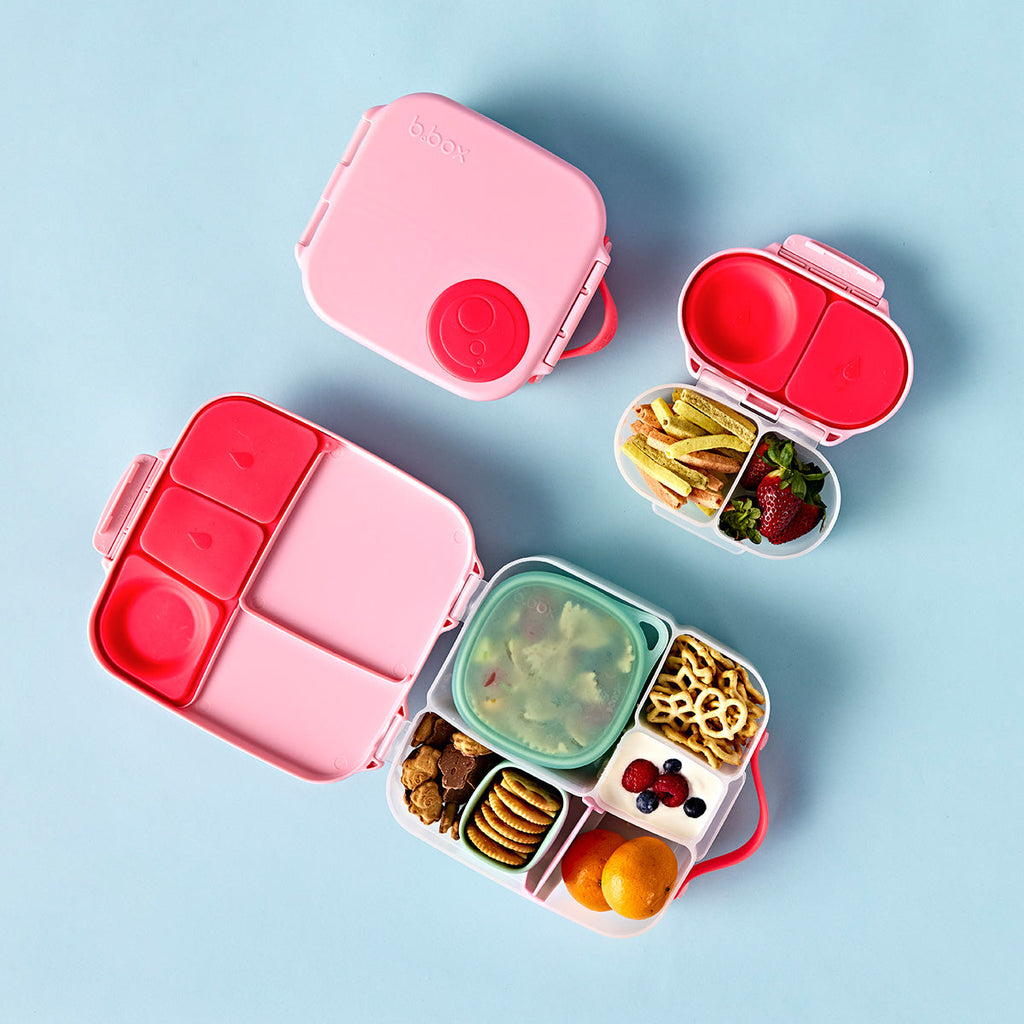 bbox flamingo fizz lunchbox Pink and red bento box with compartments filled with snacks on a light blue background